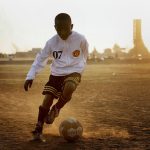 Young boys practice football in a public football ground