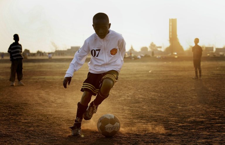 Young boys practice football in a public football ground